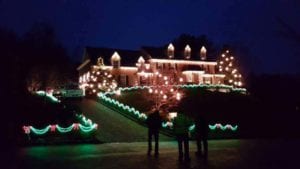 people standing outside Christmas lit house